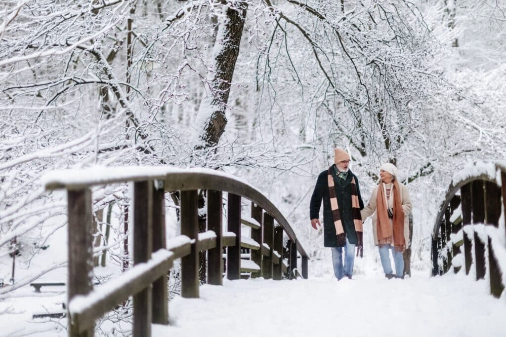 Elegant senior couple walking in the snowy park, during romantic getaways in Wisconsin winter.