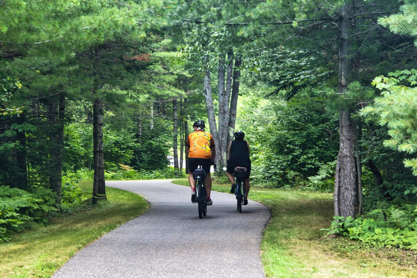 Mountain Bay State Trail: A Guide to Wisconsin's Longest Rail Trail 1 A man and woman riding bikes on a path with trees surrounding them on the Mountain Bay State Trail in Wausau, Wisconsin.